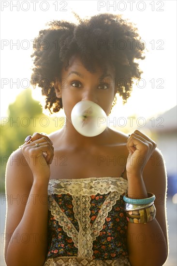 Woman blowing bubble gum bubble outdoors