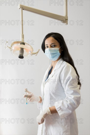 Indian dentist holding syringe near lamp