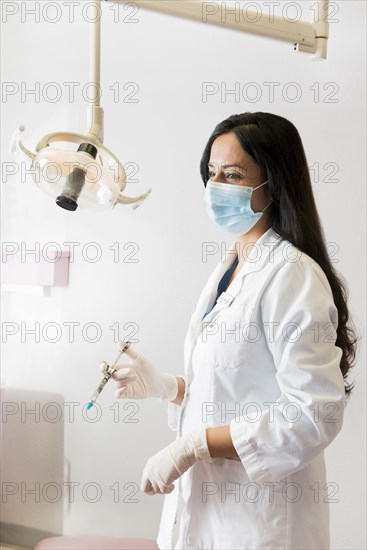 Indian dentist holding syringe near lamp