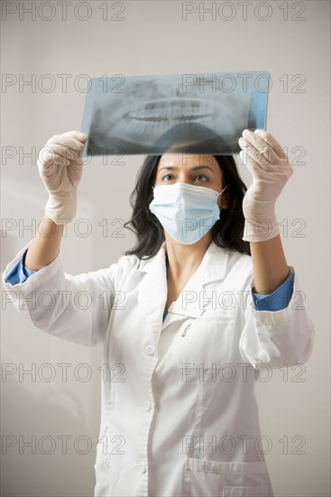 Indian dentist in surgical mask examining x-rays