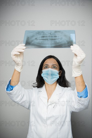 Indian dentist in face mask examining x-rays