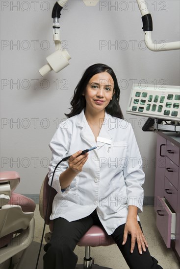 Indian dentist holding tool in office