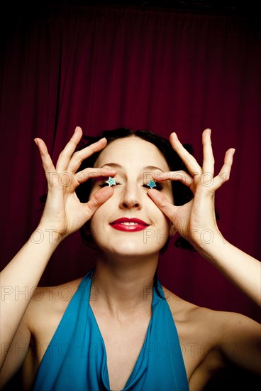 Glamorous woman holding stars over eyes