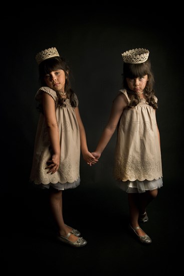 Twin girls wearing crowns and princess costumes