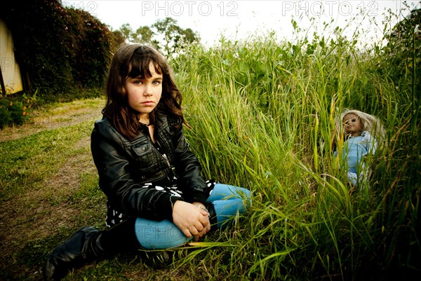 Girl playing with doll in tall grass