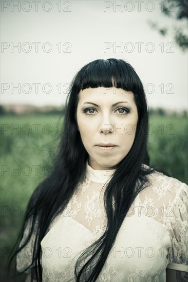 Serious woman standing in rural field