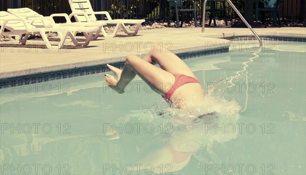 Woman in bikini diving backwards into swimming pool