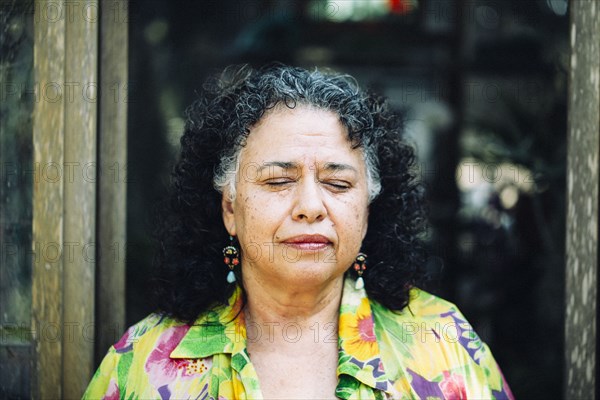 Hispanic woman standing with eyes closed outdoors