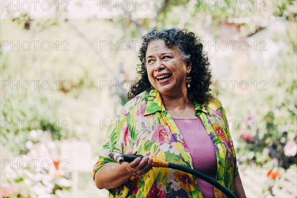 Hispanic woman watering plants in garden