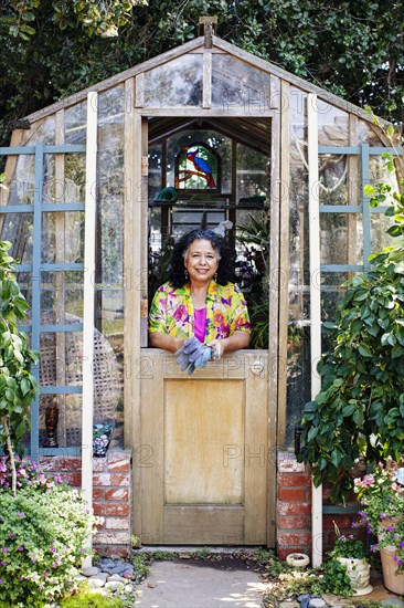 Hispanic woman smiling in garden greenhouse doorway
