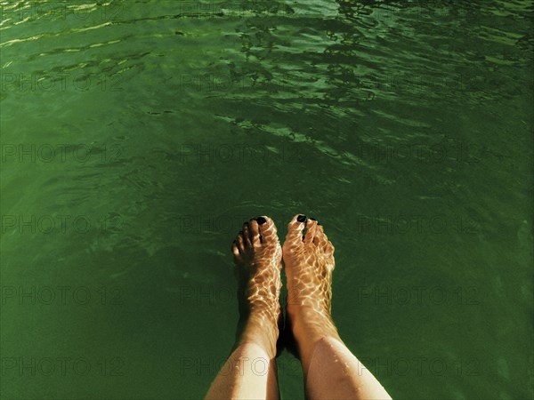 High angle view of legs of woman dangling in lake