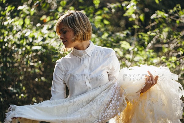 Bride holding wedding gown in garden