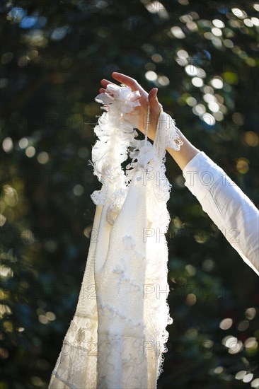 Bride holding wedding gown in garden