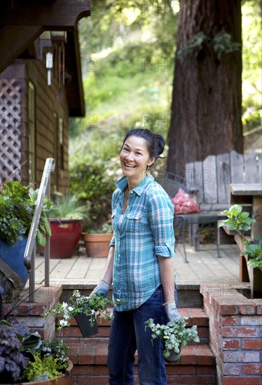 Mixed race woman holding plants in garden