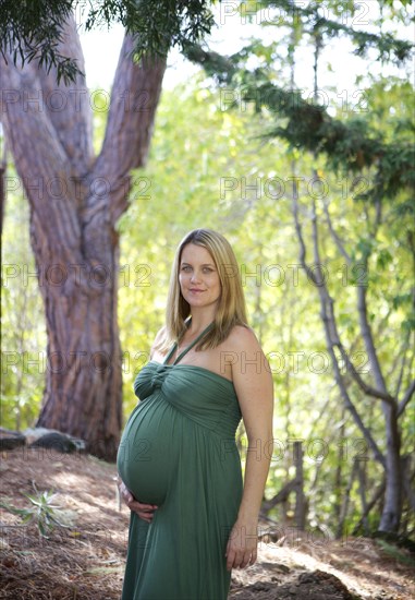 Smiling pregnant woman holding belly