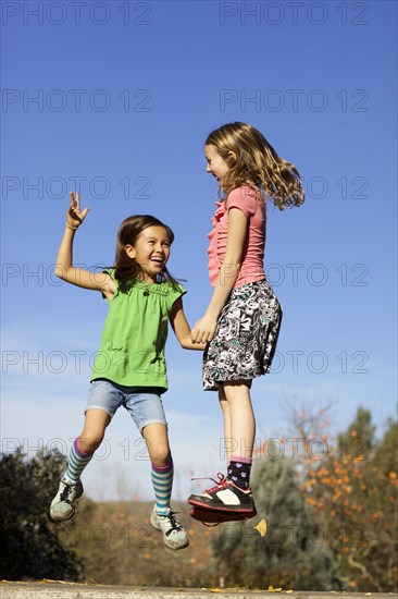 Girls jumping for joy on stone wall