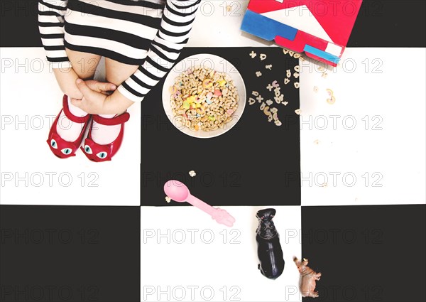 High angle view of girl spilling cereal on floor