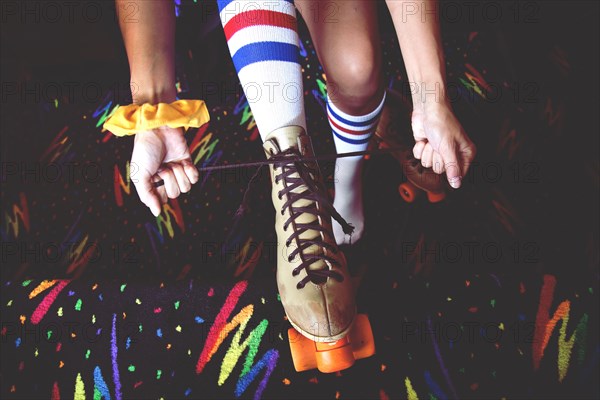 High angle view of woman lacing up roller-skates