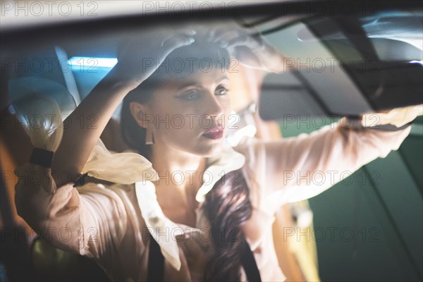 Glamorous mixed race woman checking hair in car mirror