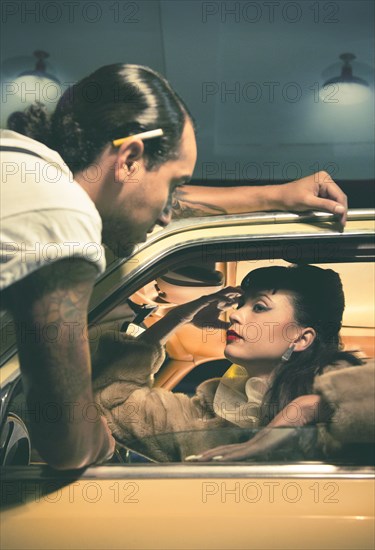 Glamorous couple talking in vintage car
