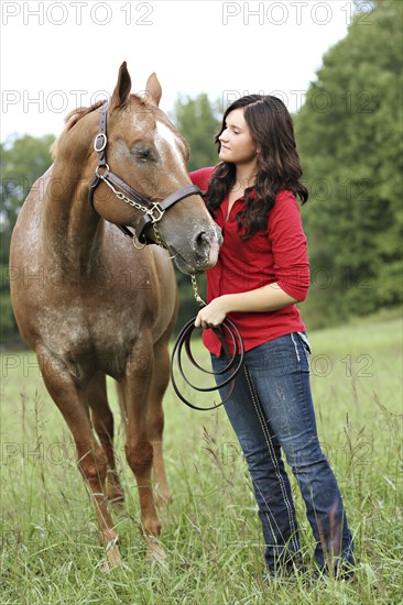 Woman walking horse in rural field