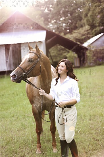 Equestrian woman walking horse in yard