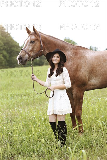 Woman walking horse in rural field