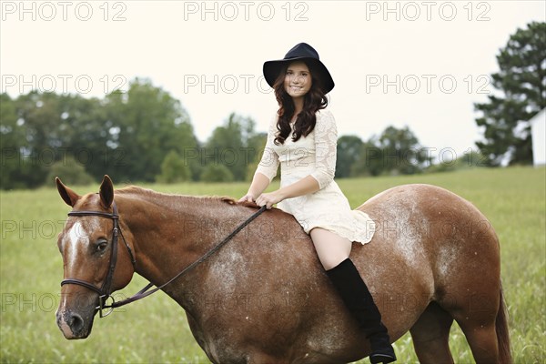 Woman riding horse in rural field