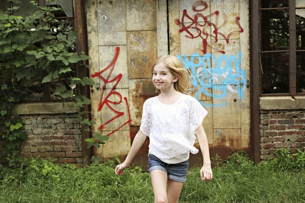 Smiling girl walking outside dilapidated building