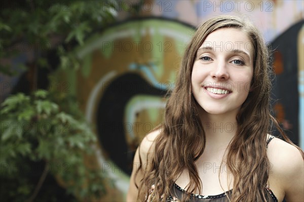 Smiling woman standing near graffiti wall