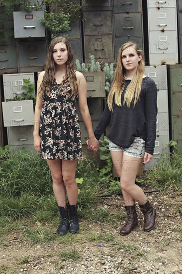 Women holding hands near dilapidated office drawers in garden