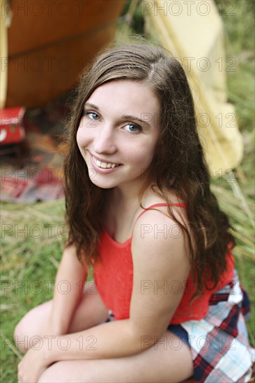 Smiling woman crouching at camping tent