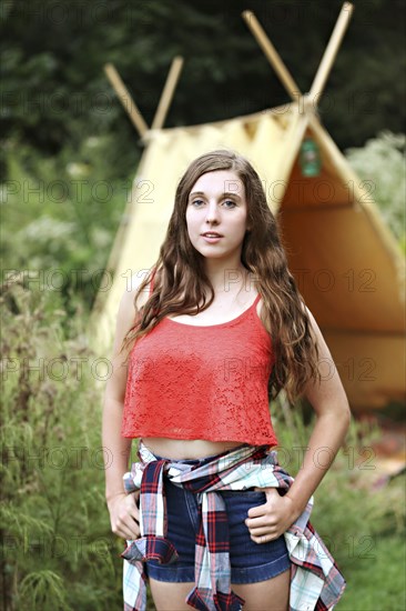 Serious woman standing at camping tent