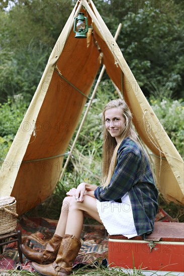 Woman sitting on cooler at camping tent