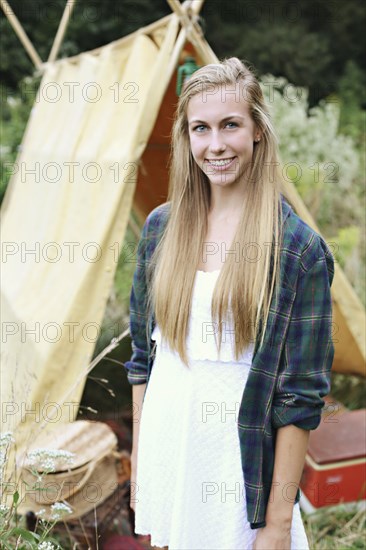 Smiling woman standing at camping tent