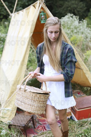 Woman carrying basket near camping tent