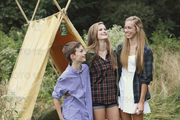 Brother and sisters smiling at camping tent