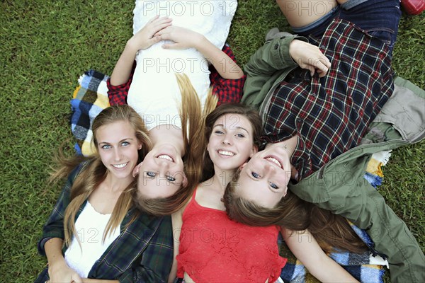 Smiling women laying on blanket in grass