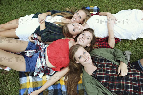 Smiling women laying on blanket in grass