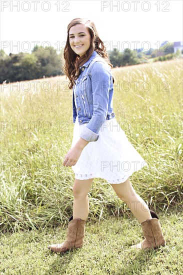 Woman walking in tall grass in field