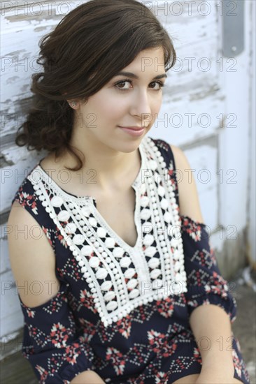 Smiling teenage girl leaning on wooden wall