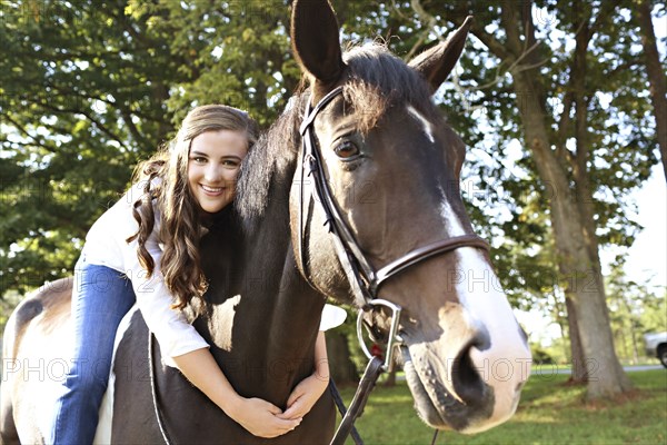 Woman hugging horse in rural field