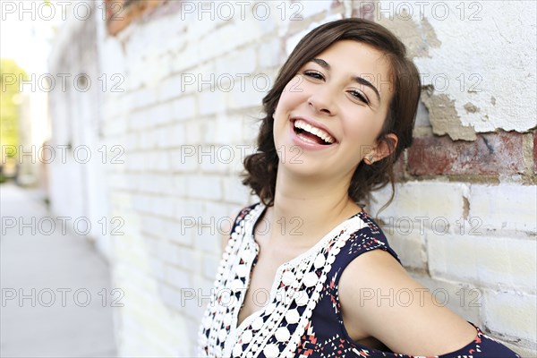 Smiling teenage girl leaning on brick wall