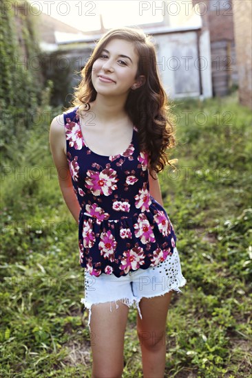 Smiling teenage girl standing in overgrown garden