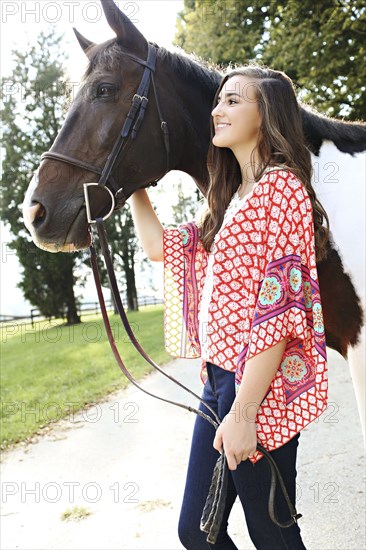 Smiling woman walking horse on dirt path