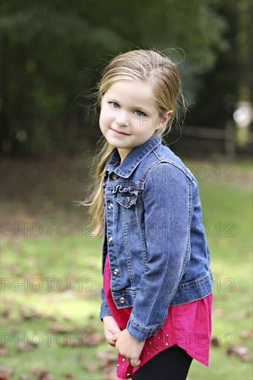 Serious girl standing in rural field