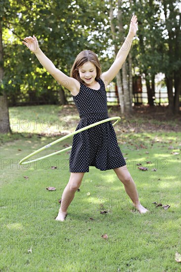 Smiling girl playing with plastic hoop in field