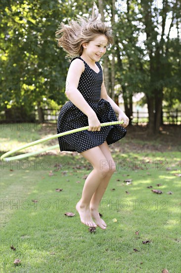 Smiling girl playing with plastic hoop in field