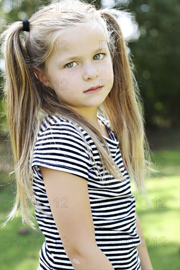 Serious girl with pigtails standing in field