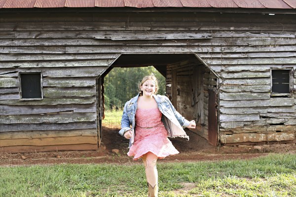 Smiling girl running near barn on rural farm